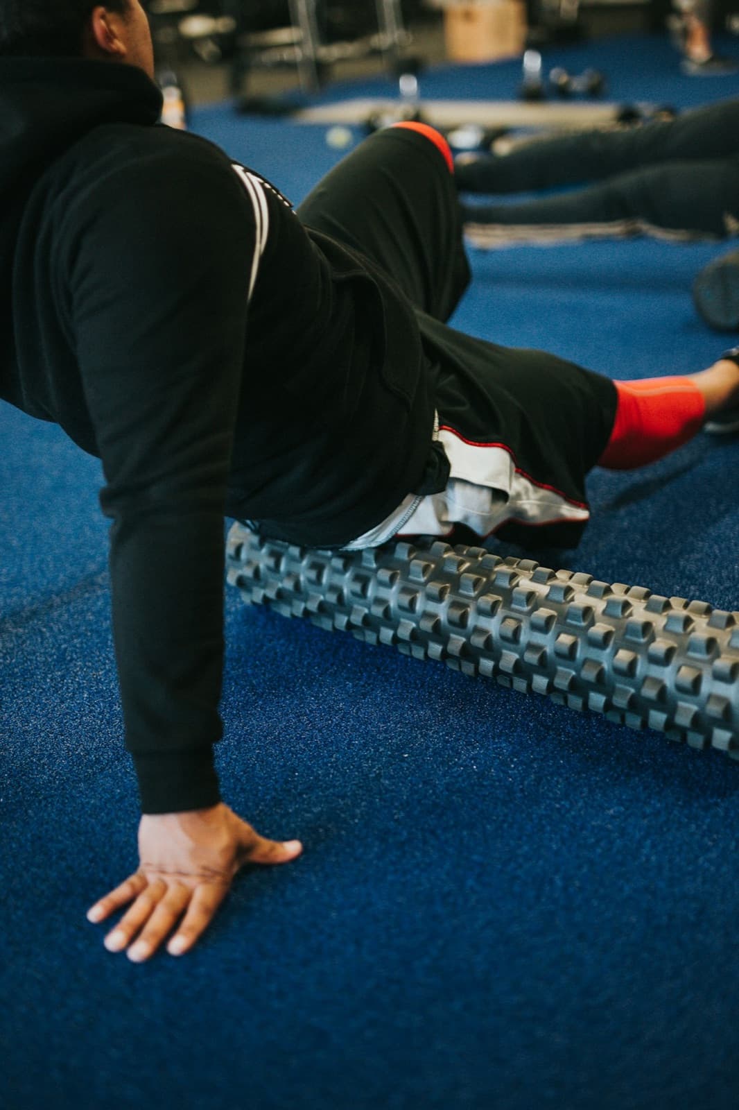 Vežbač koristi foam roller na podu teretane